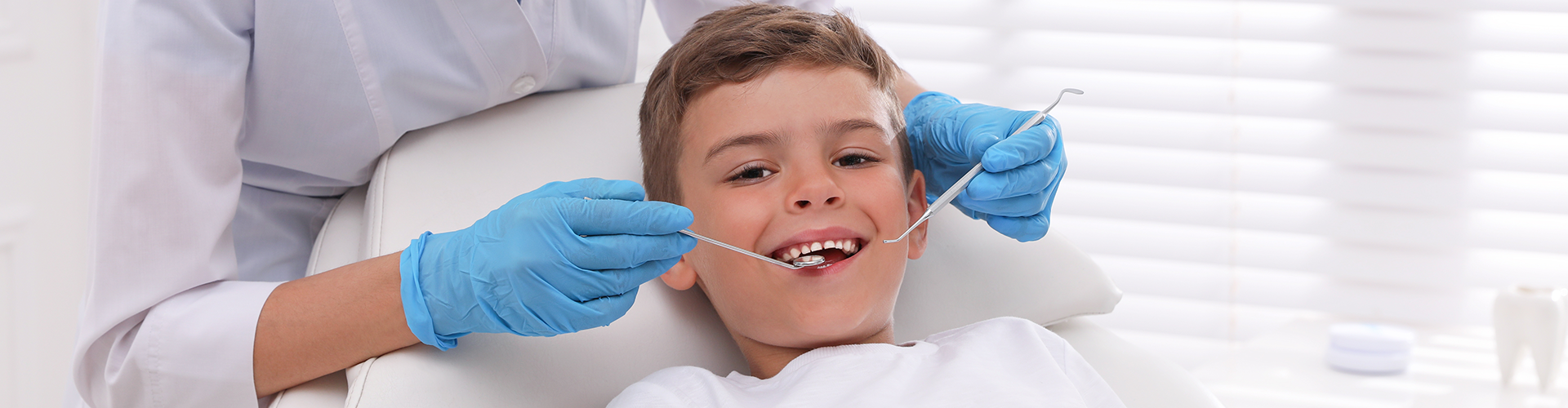 Dentist using dental tool in child's mouth.